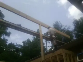 Carpenter setting a ridge beam over a new addition frame — Ice Dam Removal by Roofing Brothers in Gallion