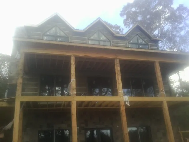 Dormers and porch framing on a large log home under construction — Roof Coating work by our crew in Gallion