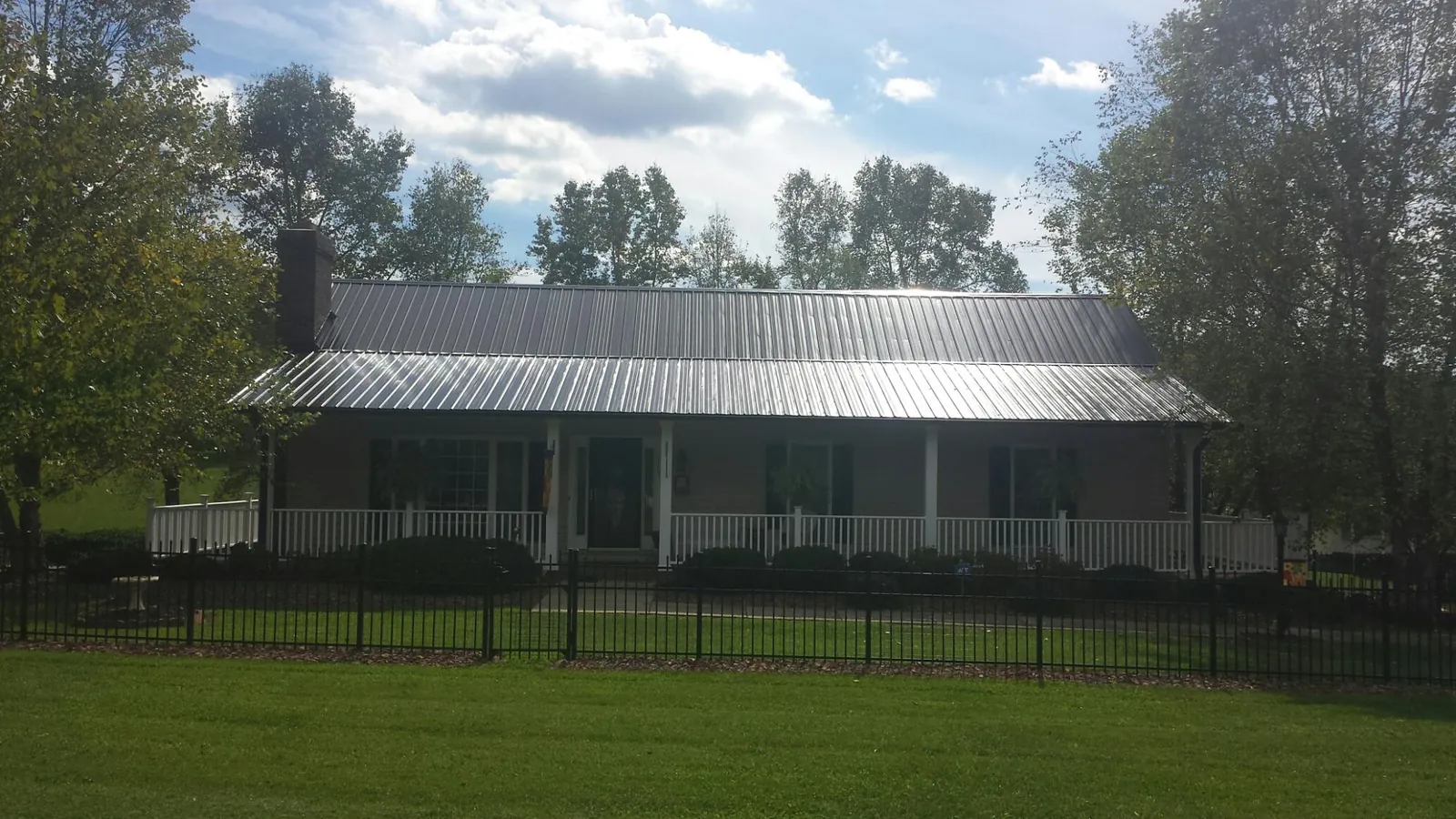 Gray metal roof on a brick ranch with a full width front porch — Gutter Guard Installation work by our crew in Gallion